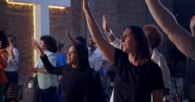 Kilisede ruhani bir toplantı sırasında insanlar el kaldırıyor. İnançlarını, bağlılıklarını ve birlikteliklerini yürekten bir duayla ifade ediyorlar.