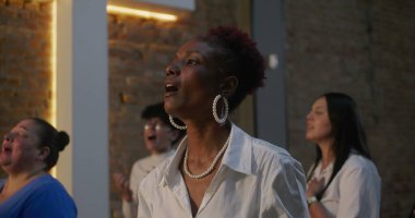 İbadet sırasında insanlar tutkuyla ve inançla şarkı söylüyor. Aydınlanmış haçın önünde duruyorlar. Ruhaniliği, bağlılığı ve toplumsal bağlantıyı temsil ediyorlar.