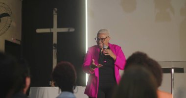 Cemaate hitap eden, mikrofon tutan, haç önünde güçlü bir vaaz veren, kilise toplantısında dikkatle dinleyen çeşitli dinleyiciler.