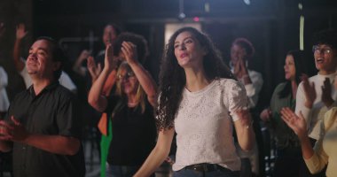 Çeşitli insan grupları ruhani bir toplantıda el çırpıyor, birlik ve inancın sevinçli bir şekilde kutlanıyor, etnik içerikli, ibadet sırasında toplum birbirine bağlanıyor.