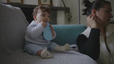 Bebek koltukta oturuyor, nesneleri çiğniyor, duyusal keşiflerle meşgul olurken anne başka tarafa bakıyor, erken çocukluk gelişimine odaklanmış çevreyi besliyor..