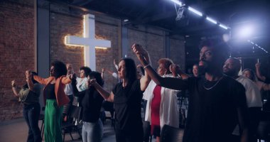 Cemaat birlik içinde el ele tutuşuyor, ibadet sırasında bir arada duruyor, dinsel ve ilham verici bir atmosferde inanç ve maneviyatı sembolize eden çapraz geçişi simgeliyor.