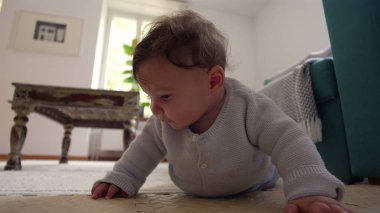 Bebek yerde yatıyor, iki koluyla yukarı itiyor, merakla ileri bakıyor, rahat bir ev ortamında çevreyi keşfediyor, emeklemeyi öğrenmenin ilk aşamaları..