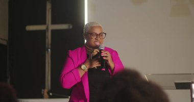 Mikrofonlu gülen hoparlör, cemaate moral verici bir mesaj iletiyor, canlı bir ceket giyiyor, inanç ve topluma tapınma üzerine kurulu bir kilise toplantısı.