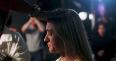 Vaiz, eli başının üzerinde olan sarışın kadını kutsadı. Ruhani tören, duygusal tapınma, sadakat ve çeşitli Hıristiyan cemaatlerine olan inanç süresince sakin bir ifade.