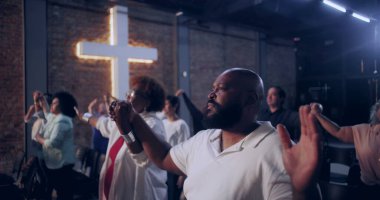 Cemaat birlik içinde el ele tutuşuyor, ibadet sırasında bir arada duruyor, dinsel ve ilham verici bir atmosferde inanç ve maneviyatı sembolize eden çapraz geçişi simgeliyor.