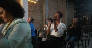 Duygusal ibadet sırasında dua eden cemaat, insanların el çırpması ve inançla el kaldırması, arka plandaki tuğla duvarda haç yakması.