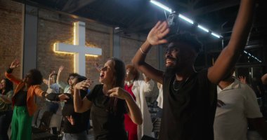 Çeşitli gruplar kilise ayini sırasında el kaldırıyor, arka planda çapraz aydınlanma, övgü, neşe ve ruhsal bağlantı ifadeleri.