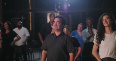 Çeşitli insan grupları ruhani bir toplantıda el çırpıyor, birlik ve inancın sevinçli bir şekilde kutlanıyor, etnik içerikli, ibadet sırasında toplum birbirine bağlanıyor.