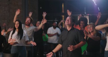 Erkek ve kadınların ibadet oturumunda el kaldırması, etnik çeşitlilikle toplanan neşeli topluluk, ruhsal bağlantı ve inanç birliğini ifade eden insanlar