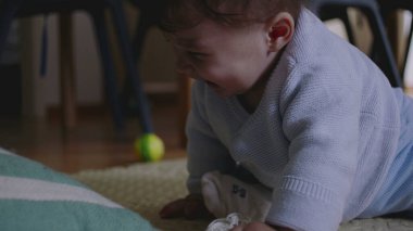 Bebek yerde yatıyor, çizgili bir yastığa uzanıyor, hayal kırıklığı ve öfke belirtileri gösteriyor, dokunarak oynamaya çabalıyor, hareket becerilerini geliştiriyor..