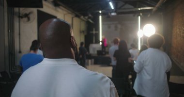 Cemaatin ayakta durduğu ve ibadet ettiği geniş bir kilise ayini sahnedeki insanların arka planı, modern kilise iç mimarisi, inanç birliği.