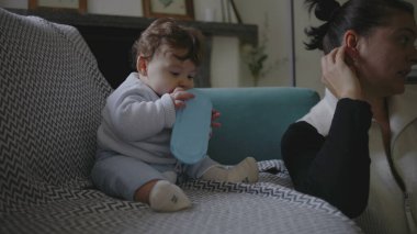 Bebek koltukta oturuyor, nesneleri çiğniyor, duyusal keşiflerle meşgul olurken anne başka tarafa bakıyor, erken çocukluk gelişimine odaklanmış çevreyi besliyor..