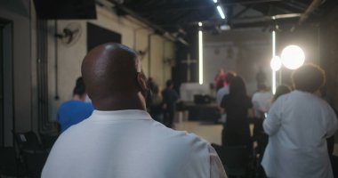 Cemaatin ayakta durduğu ve ibadet ettiği geniş bir kilise ayini sahnedeki insanların arka planı, modern kilise iç mimarisi, inanç birliği.