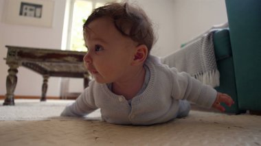 Bebek yerde yatıyor, iki koluyla yukarı itiyor, merakla ileri bakıyor, rahat bir ev ortamında çevreyi keşfediyor, emeklemeyi öğrenmenin ilk aşamaları..