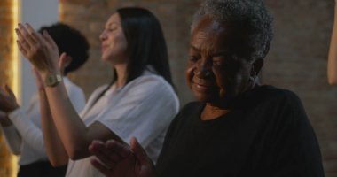 Elleri göğsünde, ibadet sırasında şarkı söyleyen ve dua eden insanlar, çeşitli cemaatlerde inanç, bağlılık ve duygusal bağlılık gösteriyorlar.