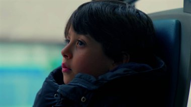 Yakından bakınca, çenesini cekete dayamış, düşünceli bir ifadeyle mesafeye bakan, hareket eden otobüsün içinde, tefekküre dalıp giden manzaraya bakan genç bir çocuğun profili.