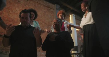 Cemaat ibadete katılıyor, ruhani bağlantıda el ele tutuşuyor, kilise ayini sırasında liderin rehberliğinde, cemaatin önünde modern evanjelik ibadeti yapıyor.