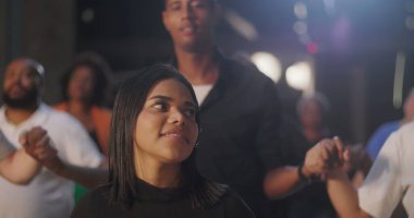 Dua eden bir grup insan, odaklanmış ifadeler, el ele tutuşmalar, duygusal anlar, birlik içinde çeşitli bireyler, kapalı bir ortamda ruhsal bağlantı