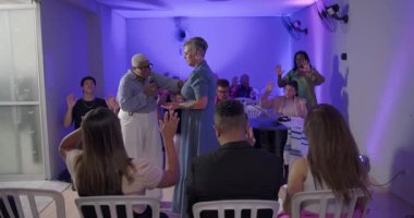 Evanjelist kilise ayini sırasında başka bir kadının omzuna dokunarak dua eden bir kadın. Cemaat birlik ve huzur içinde el ele tutuşuyor.