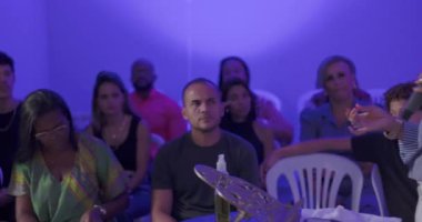 Evanjelik kilise ayininde dua eden İspanyol ve Latin hayranlar, ön sırada oturan Afrikalı Amerikalı kadın duygusal olarak duygulandı.