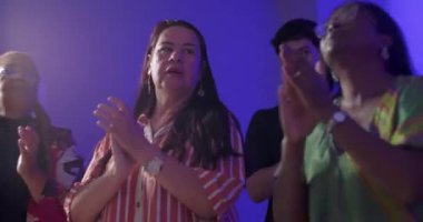 Evanjelist kilise ayini sırasında ritimli bir şekilde alkışlayan, neşeli bir koordinasyon sergileyen ve canlı ve ruhsal olarak bağlı bir cemaate olan inancı paylaşan ibadet edenler.