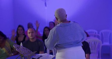 Afrika kökenli Amerikalı bir kadın vaaz veriyor, etkileyici bir yüz ifadesiyle, özenli İspanyol ve Latin hayranlarına samimi bir vaaz veriyor.