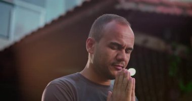 Latin Amerikalı bir adam kollarını kaldırıp gökyüzüne bakıyor. Ruhani bir bağlantı anında, dışarıda duruyor. Işığı aydınlatan bir yüzü ve arka planı var.