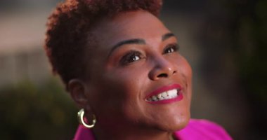 Afro-Amerikalı kadın neşe dolu bir ifade ve açık gözlerle yukarı bakıyor, pozitif ve ruhsal bağlantıyı dışardan altın ışıkta ve canlı bir şekilde yayıyor.