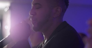 Hispanik tapınma liderinin Hıristiyan Protestan ayini sırasında mikrofona şarkı söylerken yakın profili, arka planda bulanık cemaatle çevrili