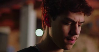 Latin kökenli genç bir adam gözleri kapalı, dudakları bastırılmış, içten bir mücadele ve duygusal gerilimi ifade ediyor.