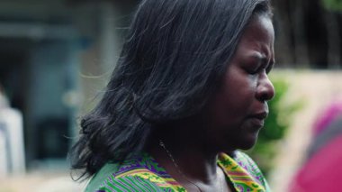 Afrika kökenli Amerikalı bir kadının gözlerini kapayarak derin duygular, sakin bir ifade ve açık hava ortamında sessiz bir güç.