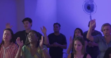 Toplumsal övgü sırasında duygusal bağ ve manevi yoğunluk gösteren ellerini kaldırarak ibadet eden bir grup insan.