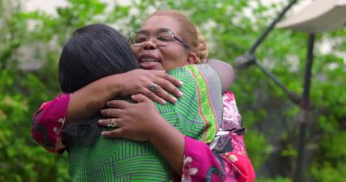 İki kadın, anlamlı bir andan sonra samimi bir şekilde kucaklaşır. Sıcak ve duygusal bir şekilde gülümser ve sımsıkı sarılırlar.