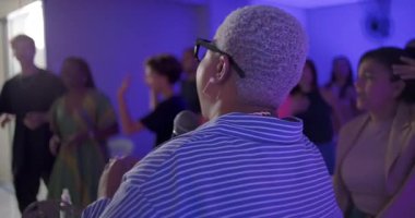 Vaiz ibadet sırasında cemaate seslenirken insanların el ele tutuşup birleşik kutlamalarda birlikte şarkı söylemelerine dikkat edin.