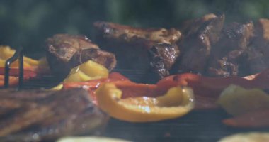 Kavrulmuş pirzola ve dolma biber dumanlı ızgarada ağır dumanlı havada, yüksek hızlı kamerayla süper yavaş çekimde yakalanır.