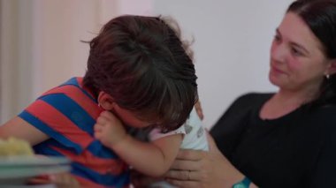 Küçük çocuk, anne tarafından kucaklanırken ağabeyini yanağından öpüyor. Sıcak bir kardeş sevgisi ve anne sevgisi anı kapalı bir aile sahnesinde yakalandı..