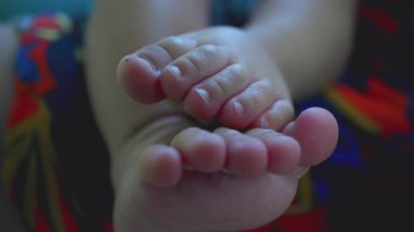 Bebeklerin ayak parmakları yavaşça birbirine bastırılmış renkli kumaşların üzerinde dinleniyor, çocukluk döneminin hassas ayrıntıları sessiz anlarda