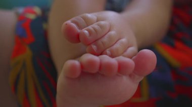 Cilt dokusuna sahip küçük bebek ayak parmaklarının detaylı görüntüleri, desenli kıyafetlerin üzerinde dinlenme, erken büyüme ve masumiyetin sembolik görüntüsü.