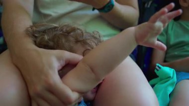 Annenin kucağında bebeğini kucağına aldığı, çocuğun dinlendiği, sessiz bir otobüste yüzünün içe dönük olduğu yakın plan.