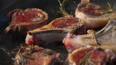 Kuzu pirzolası biberiye filizleriyle tavada kahverengileşir, yüzeyde kavrulmuş kabuk geliştirirken yağlar ve renkler yemek pişirmenin erken safhalarında değişir.