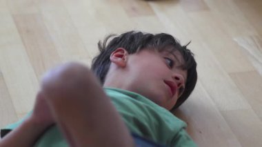 Çocuk kapıyı kapatmak için ayakları ve bacakları kullanıyor, oyuncu perspektif çocukluk özgürlüğünü, yaratıcılığı ve iç mekanda kendiliğinden yapılan hareketleri vurguluyor.