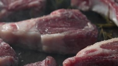 Biberiyenin üzerinde duran mermer pirzola, doğal ışık altında parlak bir yüzey ve zengin bir doku ile detaylandırılmış.