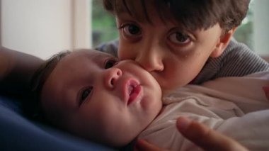 Ağabeyim bebeği yoğun bir şekilde öpüyor, sevecen ama ezici bir kardeş anı, çocukluk bağı, yakınlık, aile sevgisi, koruyucu kucaklama, duygusal bağ.