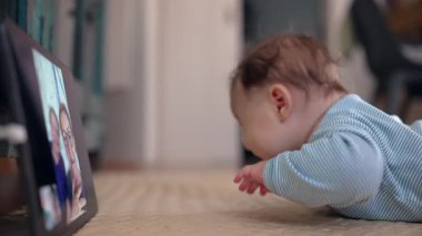 Video çağrısı sırasında bebek izleme tableti, heyecan ve merakı gösteriyor, büyükanne ve büyükbabayla dijital etkileşim, ekran yoluyla erken sosyal etkileşim