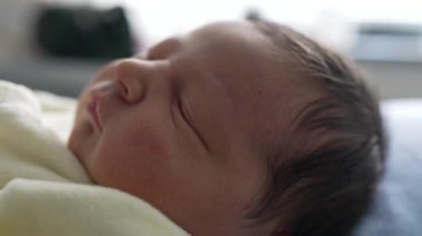 Yeni doğmuş bebek huzur içinde uyuyor, yumuşak bir teni ve rahat sarı bir kıyafeti var. Sükunet, masumiyet ve yeni başlangıçların temaları vurgulanıyor
