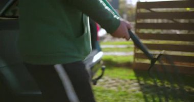 Bahçe aletlerini ahşap çitlerin yakınına koyan bir adam, güneşli bir günde bahçe bakımı ya da bahçe işleri için hazırlanan bir adam..