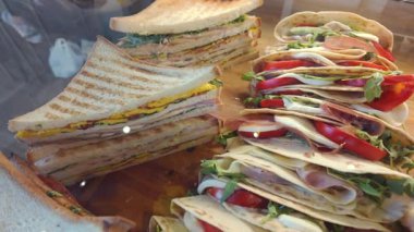 Izgara sandviç ve taze domatesli piadina paketleri, roka ve fırında jambon da dahil olmak üzere çeşitli İtalyan sandviçleri hazır.