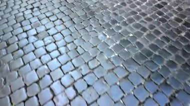 Tarihi Avrupa geçidinde metal drenaj kaplamalı ıslak kaldırım ışığı yansıtan dokulu taş kaldırım eski şehir atmosferi ve klasik cazibe yaratıyor.