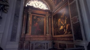 Roma, İtalya, 30 Temmuz 2025 - Caravaggio resimleri ve tarihi Roma kilisesi içindeki doğal pencere ışığıyla aydınlatılmış mermer sütunlu Barok şapeli